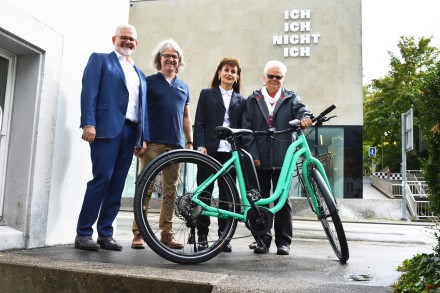 Preisübergabe: Anna Rickli (rechts) posiert mit ihrem neuen E-Bike, das ihr Regula Kiechle (zweite von rechts) vom Aargauer Roten Kreuz und Markus Schumacher (links) von der Pro Senectute Aargau übergeben haben, vor dem unterwegs.ch-Laden von Stefan Lienh